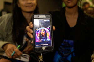 Young woman holds up phone showing album cover made using Midjourney